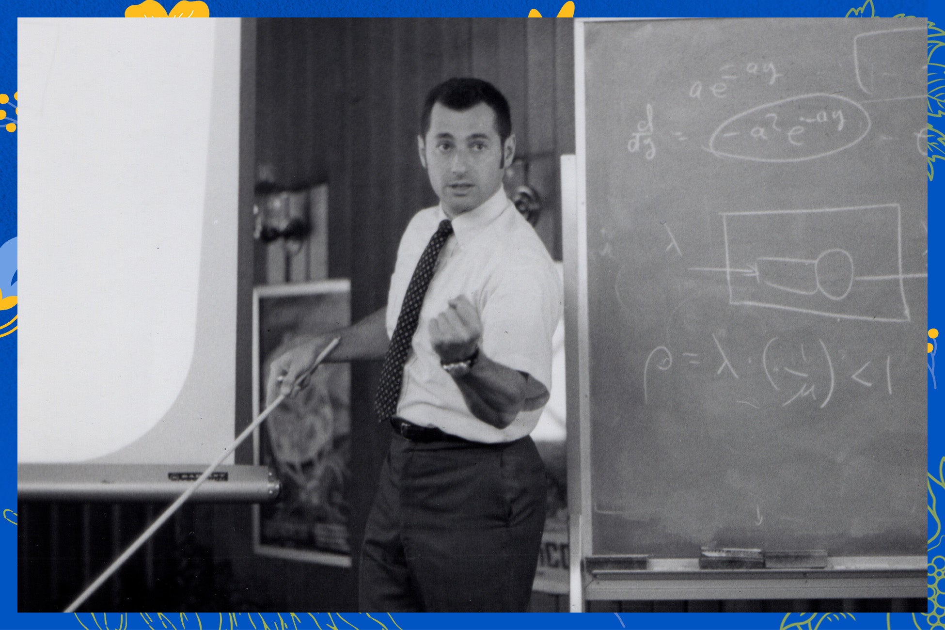 A man dressed in a tie and shirt stands in front of a blackboard, preparing to present a lesson.